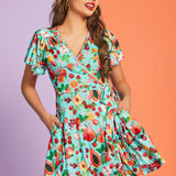 Woman wearing retro-inspired fruit print wrap dress with pockets and flutter sleeves