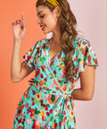 Woman wearing colorful fruit print wrap dress with flutter sleeves and vintage-inspired silhouette