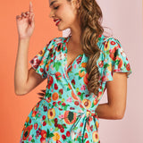 Woman wearing colorful fruit print wrap dress with flutter sleeves and vintage-inspired silhouette
