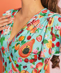 Close-up of colorful fruit print fabric featuring papaya, cherries, peaches, and citrus