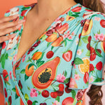 Close-up of colorful fruit print fabric featuring papaya, cherries, peaches, and citrus