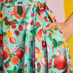 Close-up of self-tie waist and fruit novelty print on aqua fabric