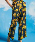 Woman wearing black pants with a yellow leaf pattern against a blue sky.