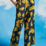 Woman wearing black pants with a yellow leaf pattern against a blue sky.