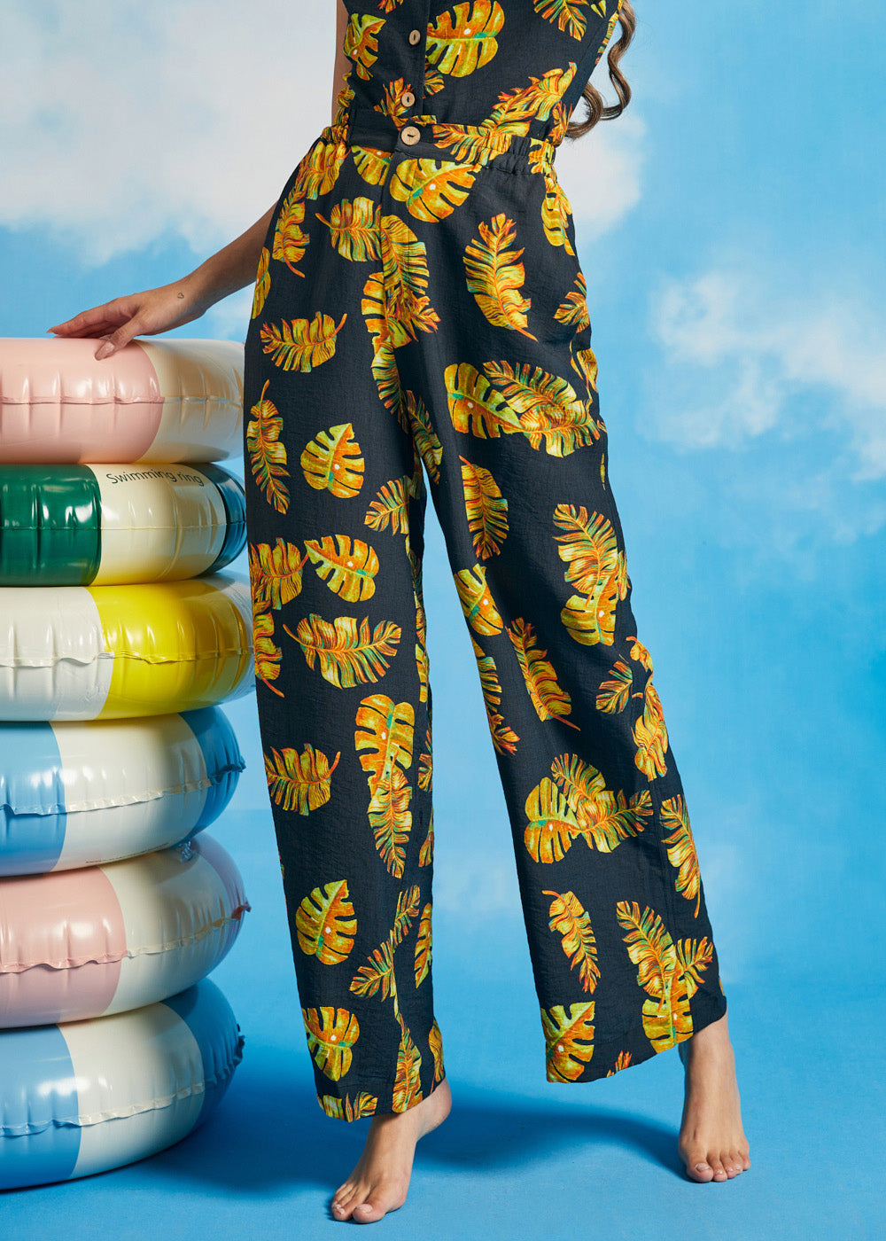 Woman wearing noir tropical palazzo pants with oversized leaf print and pockets
