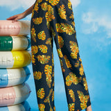 Woman wearing noir tropical palazzo pants with oversized leaf print and pockets