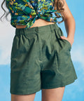 Woman wearing olive green linen blend utility shorts with tropical print crop top