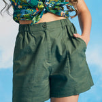 Woman wearing olive green linen blend utility shorts with tropical print crop top