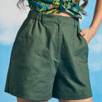 Close-up of front closure and oversized patch pockets on green shorts