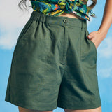 Close-up of front closure and oversized patch pockets on green shorts