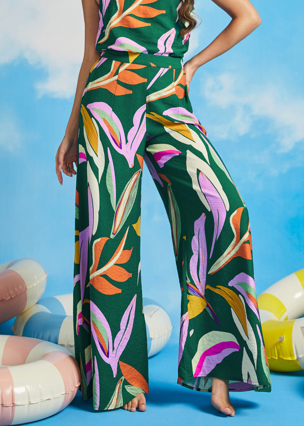 Woman posing in abstract tropical print palazzo pants with wide flowing legs