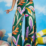 Woman wearing oversized tropical print palazzo pants with breezy resort-inspired silhouette