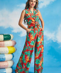 Woman wearing tropical print wide-leg palazzo trousers with monstera leaves and orchid flowers