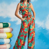 Woman wearing tropical print wide-leg palazzo trousers with monstera leaves and orchid flowers
