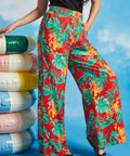 Woman modeling high-waisted tropical print trousers with black sleeveless top