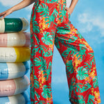 Woman modeling high-waisted tropical print trousers with black sleeveless top