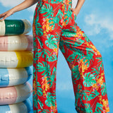 Woman modeling high-waisted tropical print trousers with black sleeveless top