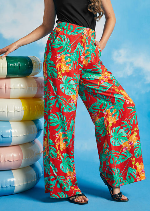Woman modeling high-waisted tropical print trousers with black sleeveless top