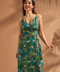 Woman wearing a jungle print faux-wrap midi dress with tropical leaves and safari animals.