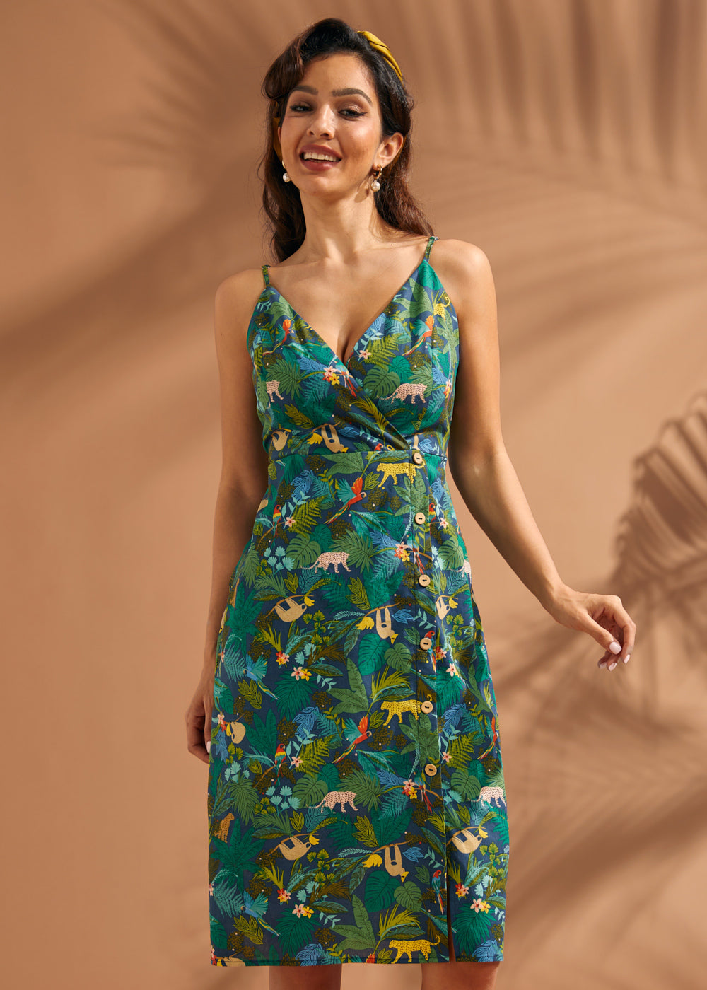 Woman wearing a jungle print faux-wrap midi dress with tropical leaves and safari animals.