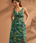 Woman wearing a cotton safari print dress with pockets and colorful rainforest motif.