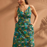 Woman wearing a cotton safari print dress with pockets and colorful rainforest motif.