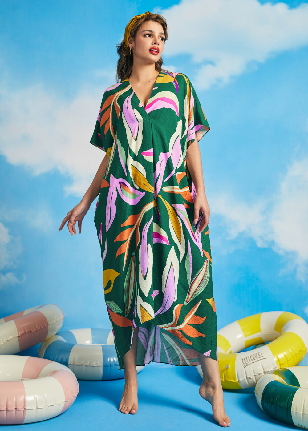 Woman wearing green tropical print maxi caftan dress with oversized botanical pattern and V-neckline