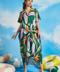 Woman wearing green tropical print maxi caftan dress with oversized botanical pattern and V-neckline