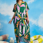 Woman wearing green tropical print maxi caftan dress with oversized botanical pattern and V-neckline