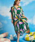 Woman walking in oversized tropical resort caftan dress with flowing drape