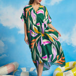 Woman walking in oversized tropical resort caftan dress with flowing drape
