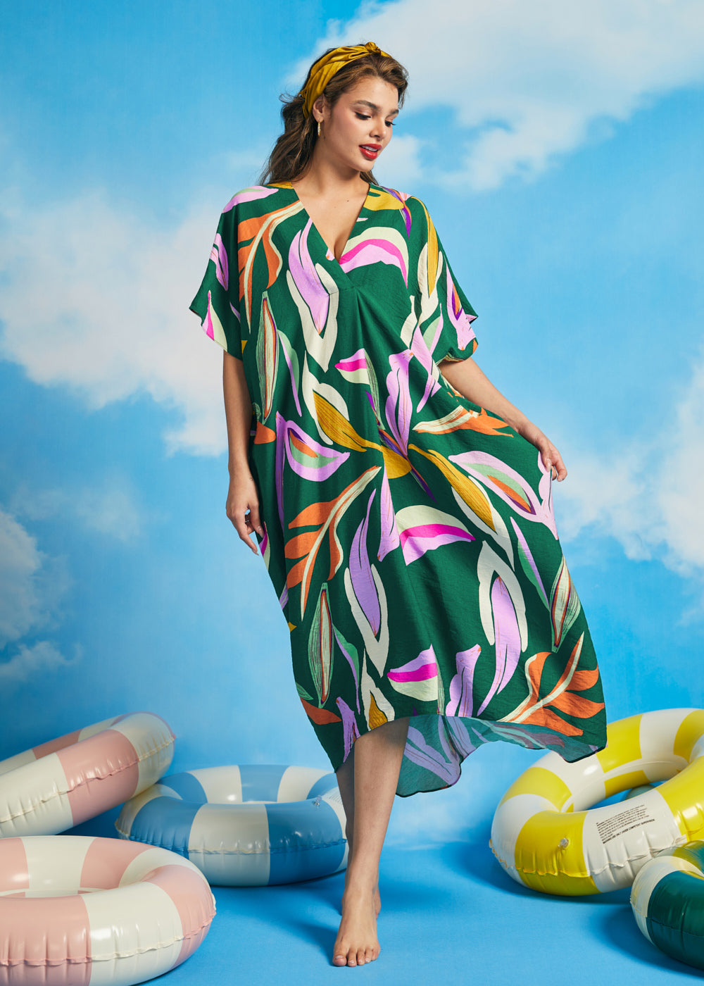 Woman walking in oversized tropical resort caftan dress with flowing drape
