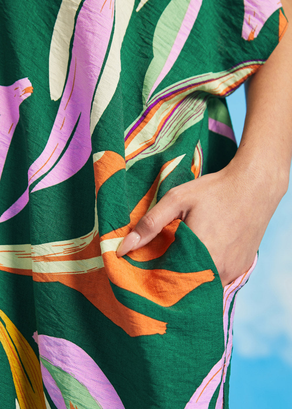 Close-up of side pocket detail on green tropical print caftan dress