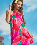 Woman wearing tropical pink and green halter dress with oversized floral print and mini silhouette