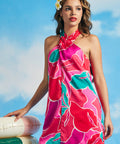 Close-up of tropical floral print and twisted neckline detail on satin-like mini dress