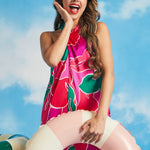 Woman posing with pastel pool float while wearing retro tropical floral mini dress