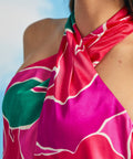 Close-up detail of twisted halter neckline on pink tropical floral dress