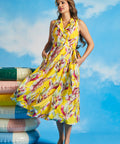 Woman wearing yellow tropical wrap midi dress with pockets and side tie detail