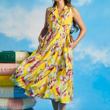 Woman wearing yellow tropical wrap midi dress with pockets and side tie detail
