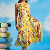 Woman holding skirt of yellow tropical leaf print wrap midi dress with pockets