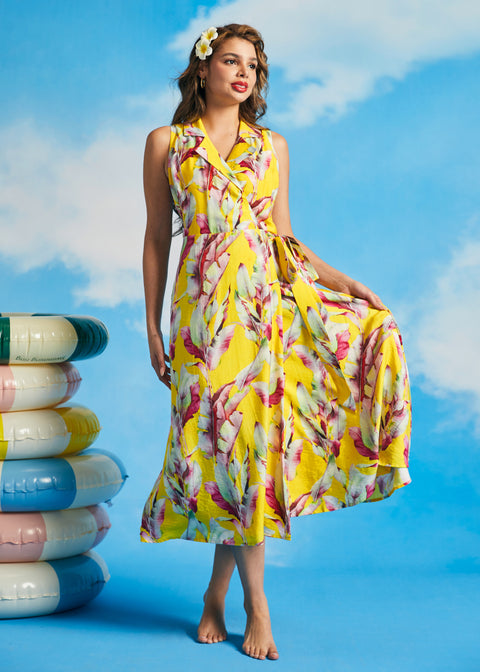 Woman holding skirt of yellow tropical leaf print wrap midi dress with pockets