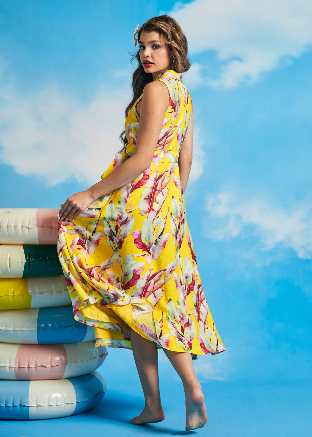 Back view of yellow tropical leaf print sleeveless midi dress with flowing skirt