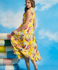 Back view of yellow tropical leaf print sleeveless midi dress with flowing skirt