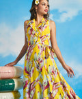 Woman posing in flowing yellow tropical leaf print midi dress with vintage resort-inspired silhouette