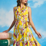 Woman posing in flowing yellow tropical leaf print midi dress with vintage resort-inspired silhouette