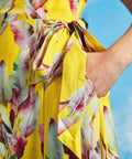 Close-up of tie waist detail on yellow tropical leaf print wrap midi dress