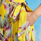 Close-up of tie waist detail on yellow tropical leaf print wrap midi dress