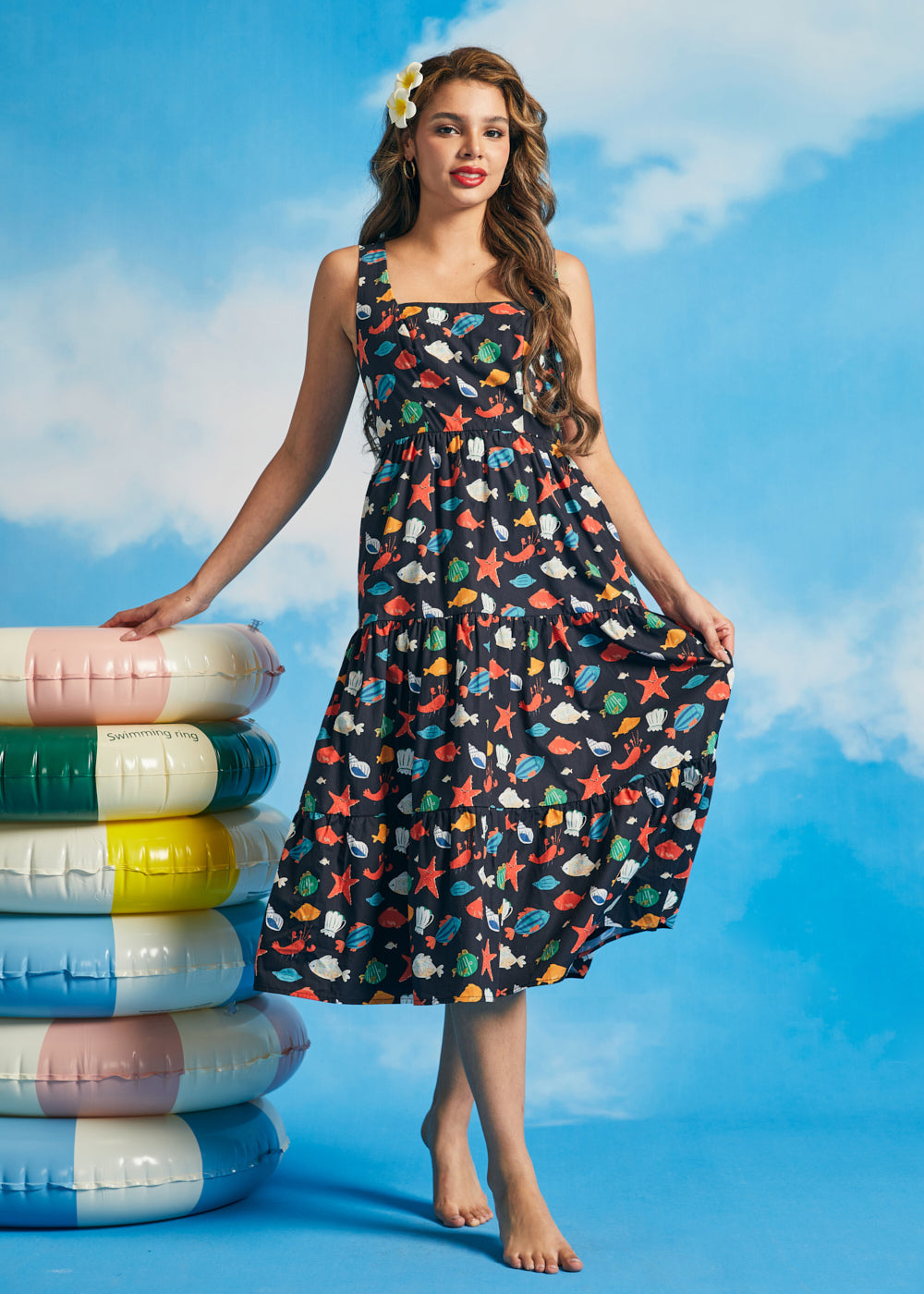 Woman wearing retro-inspired navy cotton midi dress with tiered skirt and ocean-themed print