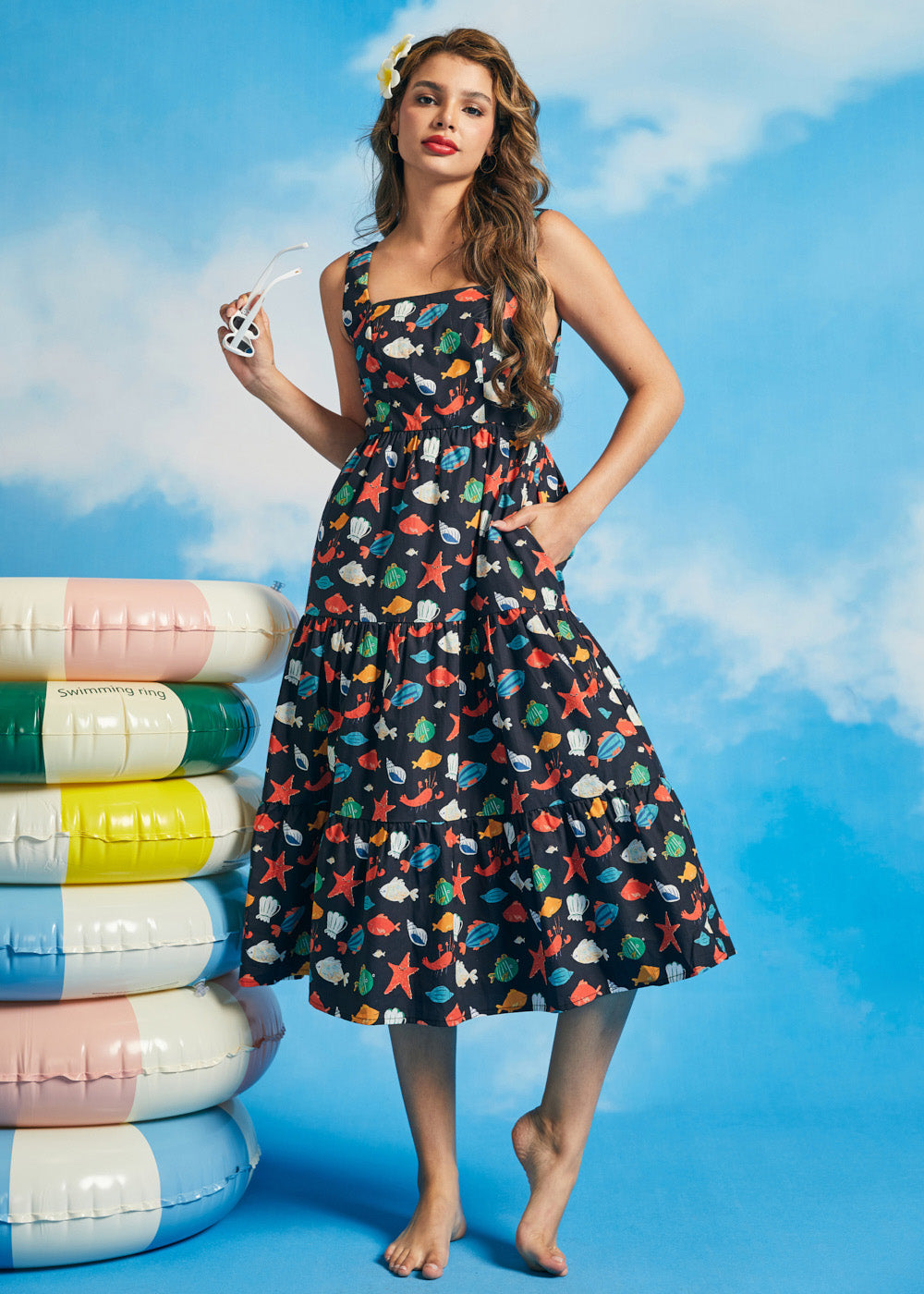 Woman wearing navy tiered fit-and-flare midi dress with colorful ocean print and square neckline