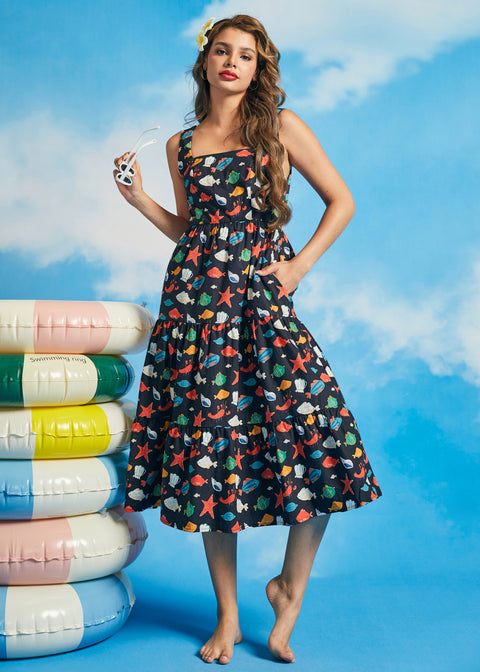 Woman wearing navy tiered fit-and-flare midi dress with colorful ocean print and square neckline